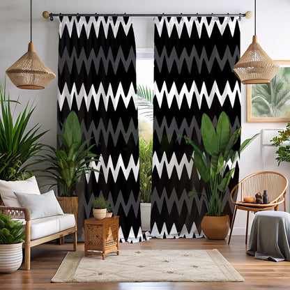 A set of geometric mudcloth print blackout curtains in black, gold, and gray, displayed in a room setting with a window, plants, and furniture.