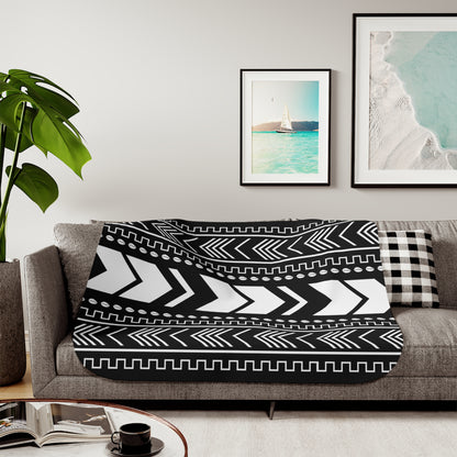 Black and white patterned throw blanket on a gray sofa with framed artwork on the wall.