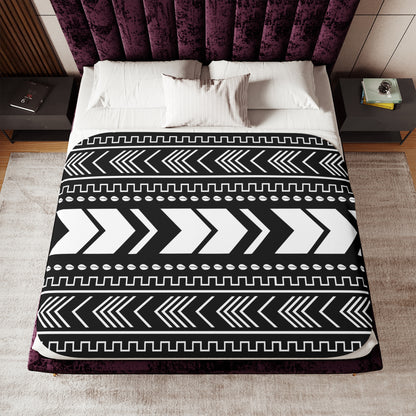 Bed with a black and white patterned comforter in a bedroom setting.