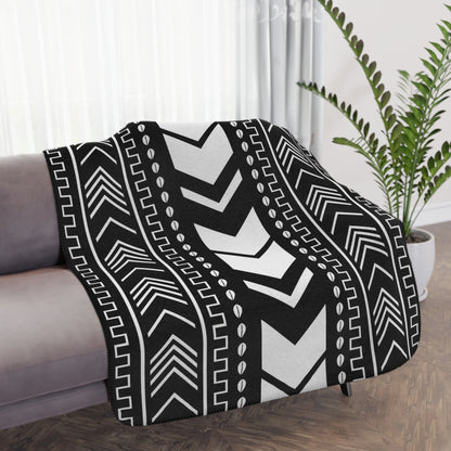 Black and white patterned throw blanket draped over a sofa in a living room.