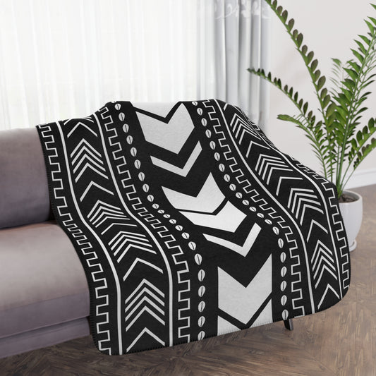 Black and white patterned throw blanket draped over a sofa in a living room.