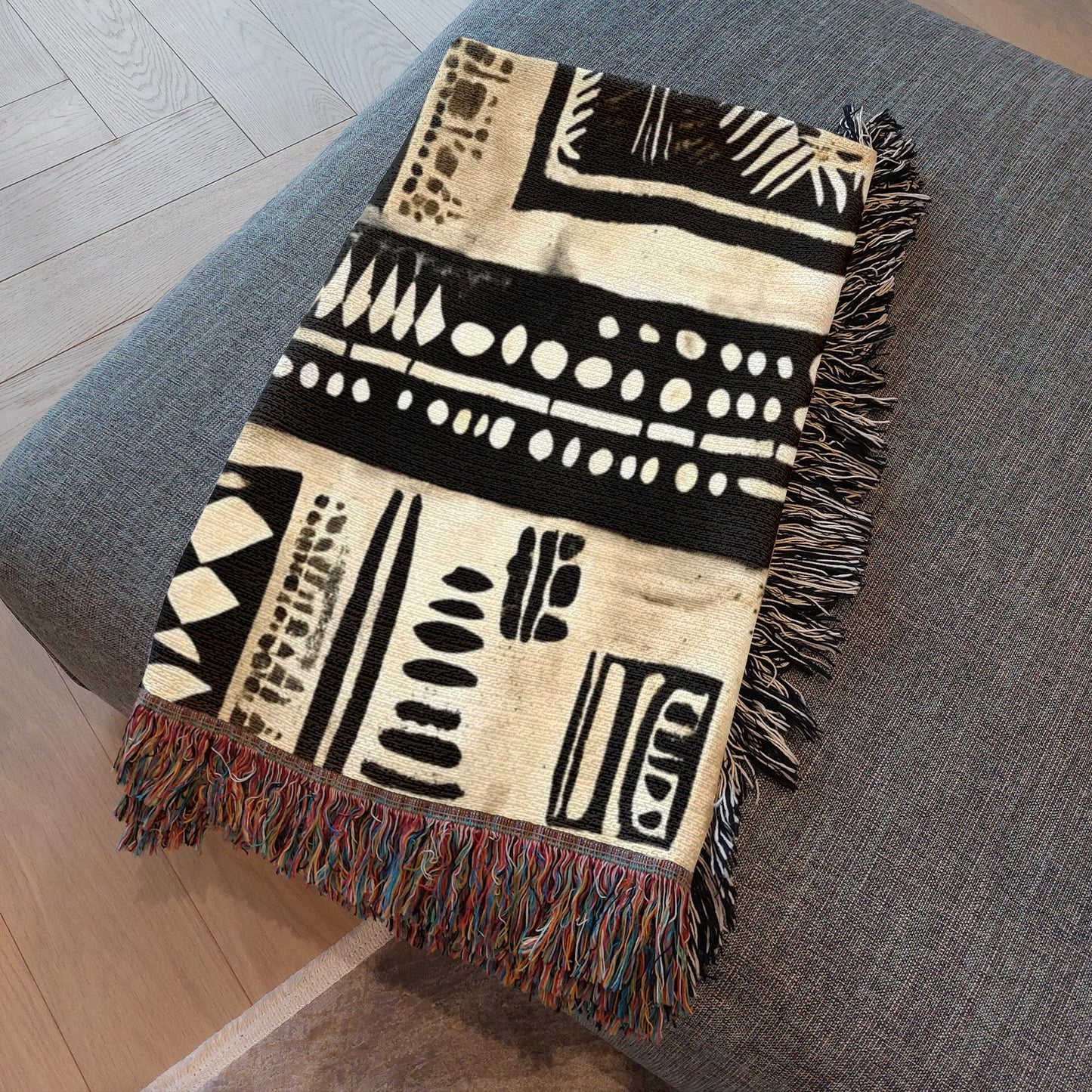 Decorative blanket with black and white patterns on a gray surface