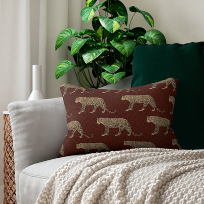 A lumbar pillow with a leopard print pattern, placed on a sofa next to a green cushion and a wicker chair, with a potted plant and a cozy blanket in the background.