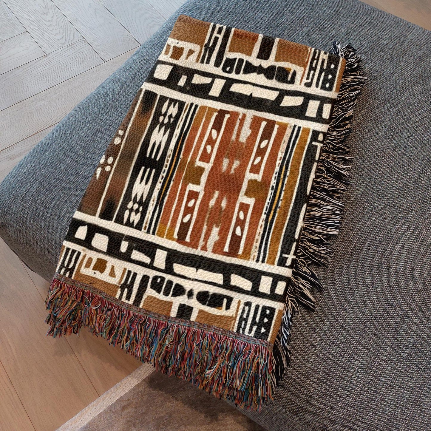 Mudcloth Patterned blanket with fringes on a gray surface