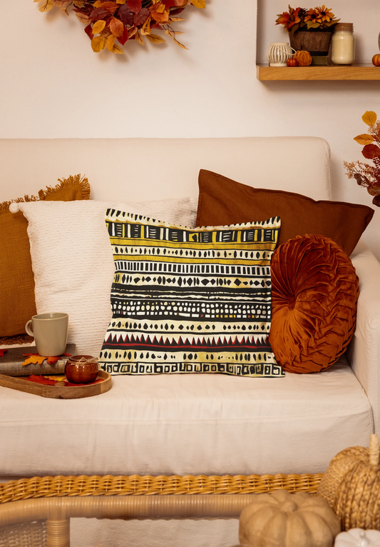Patterned pillow on beige couch with fall decor, autumn leaves, and cozy home accents