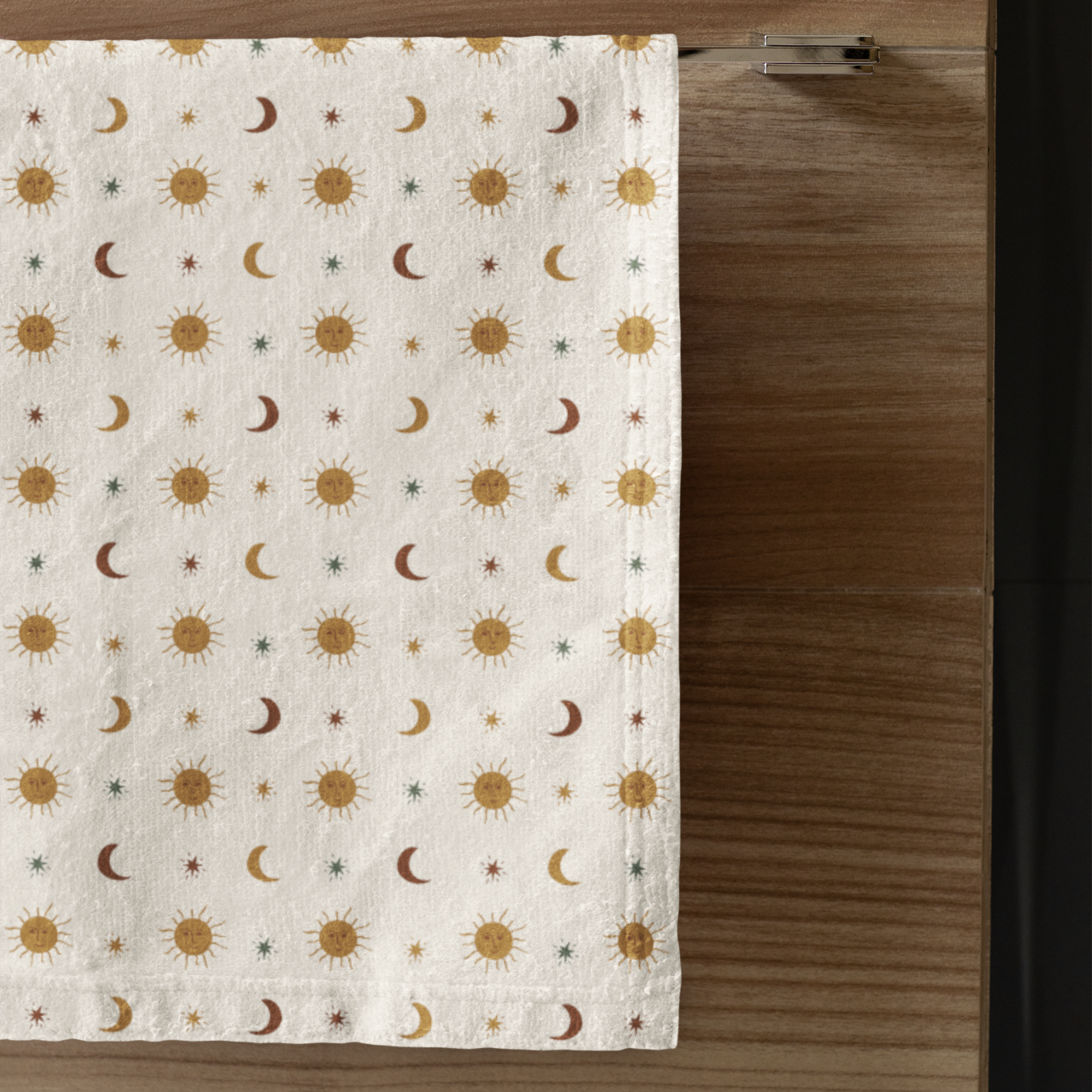 Patterned towel with sun and moon design on a wooden surface